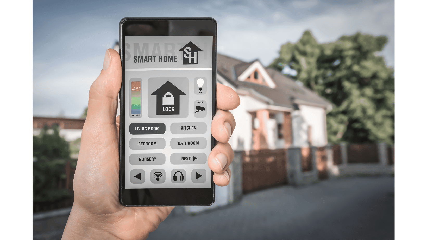 Hand holding a smartphone displaying a smart home control app in front of a house.